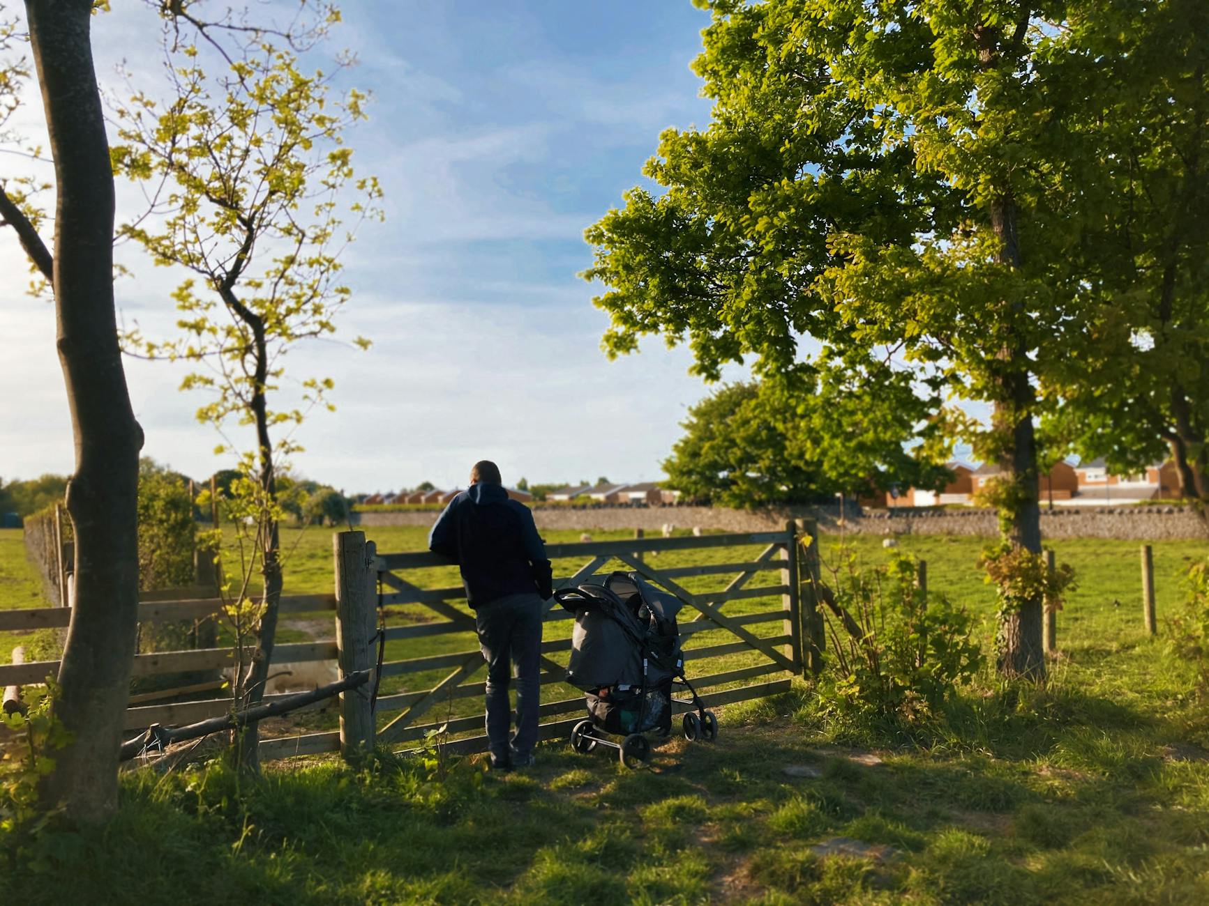 anonymous man with baby carriage standing near fence